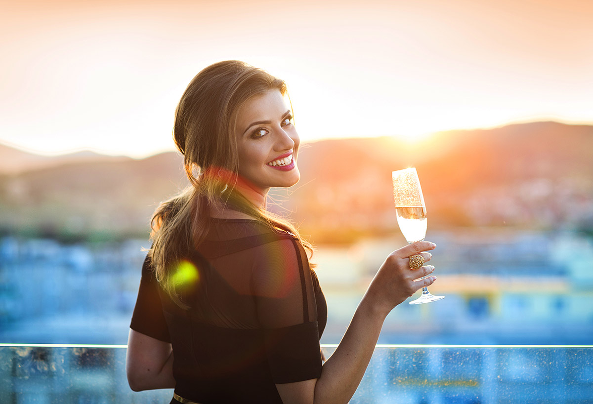 Girl holding a glass of Champagne looking into sunset