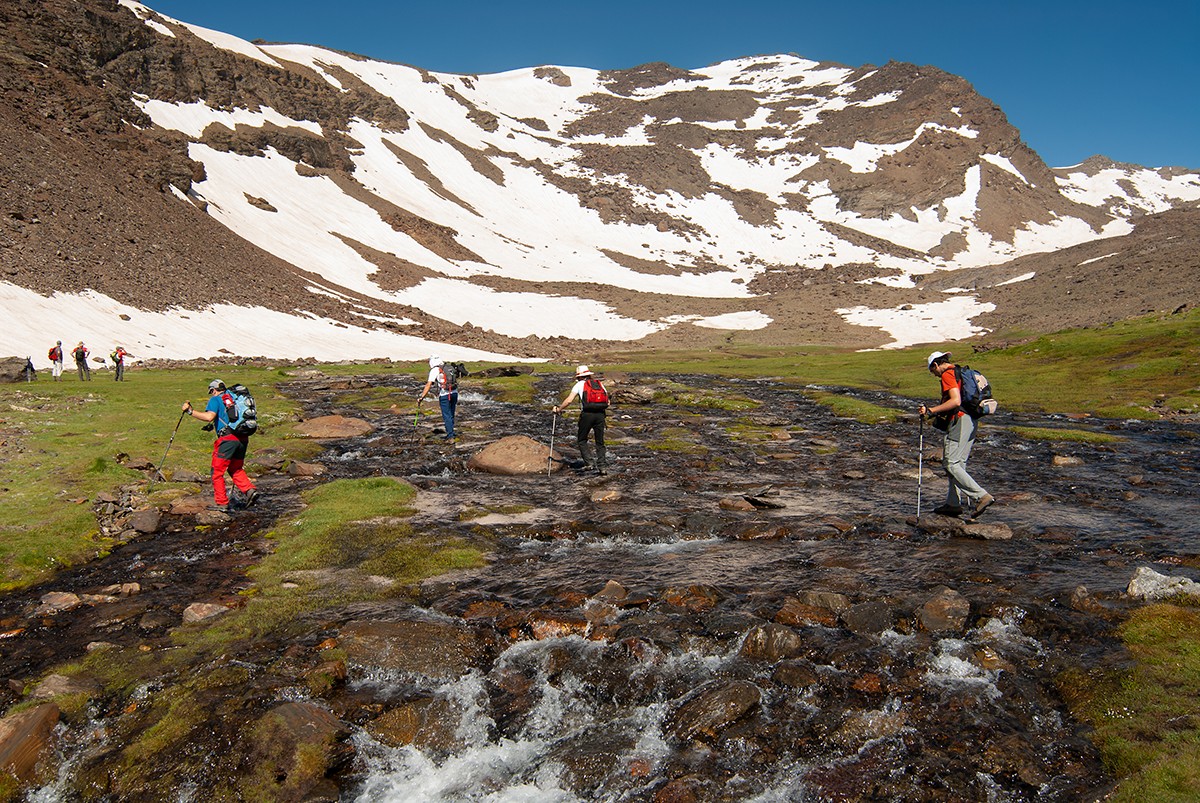 Hikers crossing the channel of the Hondera lagoon in the Sierra Nevada National Park