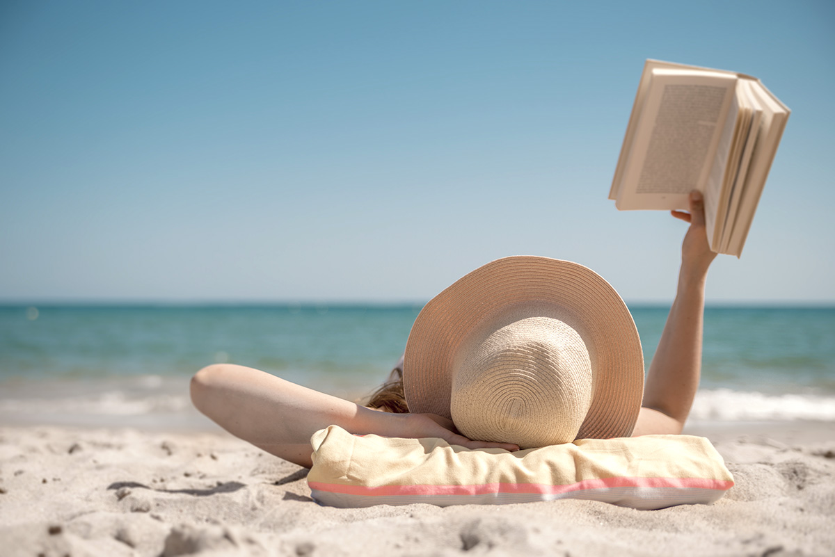 Girl lying on beach reading book