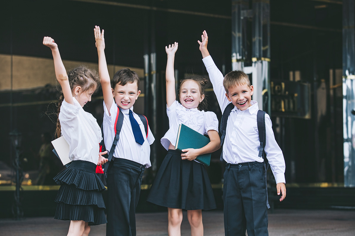Four Happy children raising hands at school