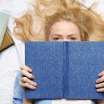 Girl lying on a bed and reading a book